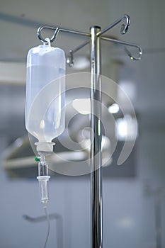 Intravenous or Iv fluids drip bottle hanging on a metal pole in hospital emergency room