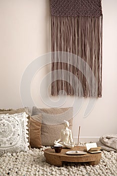 Intrerior design of cozy composition of meditation living room interior with beige carpet, pillows, macrame and personal