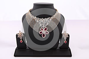 intricate and beautiful choker necklace with red white dimonds and matching earrings on black background.