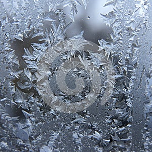 Intricate frost patterns form on a window, displaying a delicate array of ice crystals