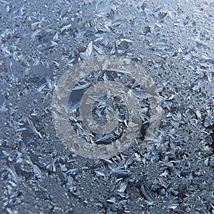Intricate ice crystals form a delicate frost pattern on a window. The formations