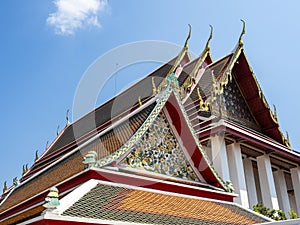 Intricate roof details of the Wat Pho Temple with blue sky behind in Bangkok, Thailand