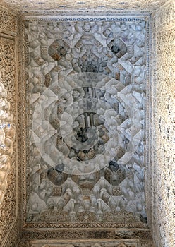 Intricately designed ceiling surrounded by intricately carved walls in the Alhambra in Granada, Andalusia, Spain.