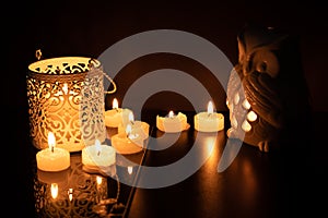 Intrincate metal candle holder with a lighting scented candle are displayed on the blak stone table in the dark living room of the