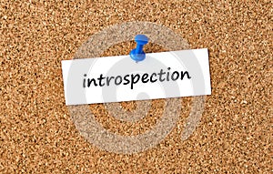 Introspection. Word written on a piece of paper, cork board background