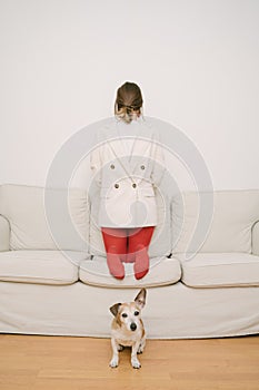 Introvert behavior. a girl in red tights and a jacket stands back to front on the couch.