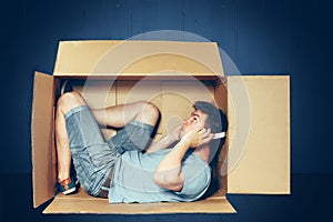 Introvert concept. The man sitting inside box and working with laptop