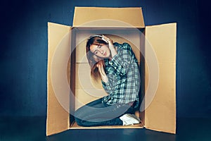 Introvert concept. Woman sitting inside box and working with laptop