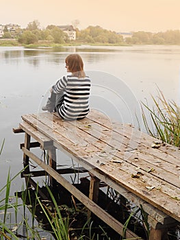 Introvert woman sits on edge of pier