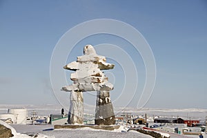 Inukshuk or Inuksuk landmark covered in snow found on a hill in the community of Rankin Inlet, Nunavut