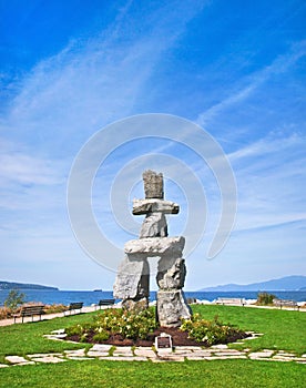 Inukshuk, symbol of the 2010 winter olympic games, with blue sky at English Bay in Vancouver, British Columbia, Canada