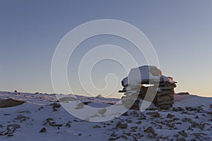 Inuksuk landmark covered in snow found on a hill near the community of Cambridge Bay