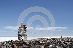 Inuksuk landmark with frozen bay in the background