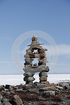 Inuksuk landmark with frozen bay in the background