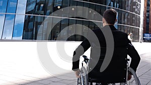 Invalid businessman in wheelchair move near modern business centre