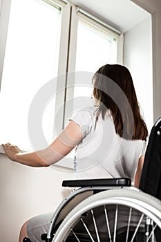 Invalid or disabled woman sitting wheelchair looking window daylight