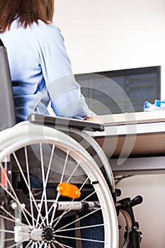 Invalid or disabled woman sitting wheelchair working office desk computer