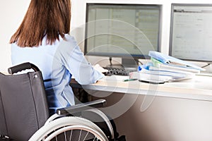 Invalid or disabled woman sitting wheelchair working office desk computer