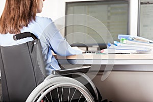 Invalid or disabled woman sitting wheelchair working office desk computer photo