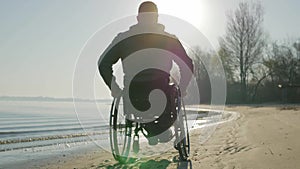 Invalid rides along beach in wheelchair, disabled faith in future, man