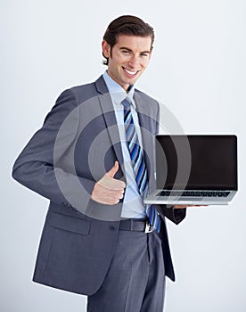 Invaluable business tool. A young businessman endorsing a laptop with a thumbs up.