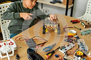 Invent. Close up of a boy using screwdriver while fixing bolts on a robot vehicle. Smart kids and STEM education.