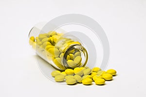 Inverted glass vial with scattered small yellow pills