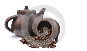 Inverted mug with coffee beans on the background of a clay teapot, isolated on white