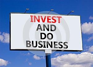 Invest and do business symbol. Concept word Invest and do business on beautiful big white billboard. Beautiful blue sky cloud