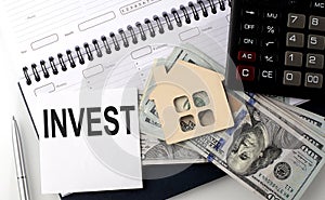 INVEST - the inscription of text on the sticker on planning with dollars and calculator