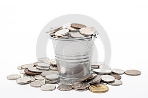 Invest money, smart finances and cash profits concept with metal coin bucket with some coins spilling around isolated on white