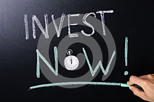 Invest Now Concept Written On Blackboard