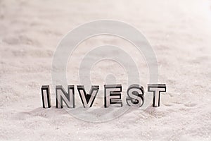 Invest word on white sand