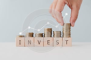 INVEST word on wooden cubes block under stack of coin and graph. For Financial investment growth or investment decision in