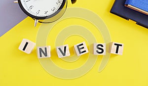 Invest word written on wooden cubes , business concept