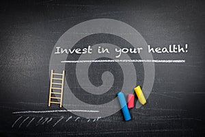 Invest in your health. Text, miniature stairs and colorful pieces of chalk on a chalkboard background