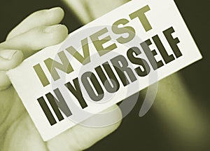 Invest in Yourself message on business card shown by a businessman. Education importance concept