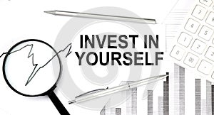 INVEST IN YOURSELF text on document with pen,graph and magnifier,calculator