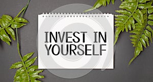 INVEST IN YOURSELF text with real leaves tropical jungle background.flat lay design