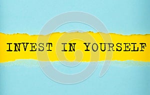 INVEST IN YOURSELF text on the torn paper , yellow background