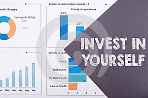 Invest in yourself text written in a gray paper on a financial charts