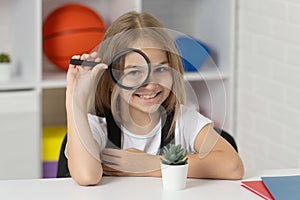 investigate with loupe. science and childhood. teen girl looking at plant through magnifier