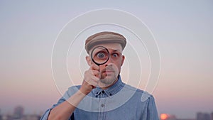 Investigator man making big eye using magnifying glass