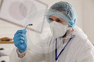 Investigator in protective suit examining evidence at crime scene indoors