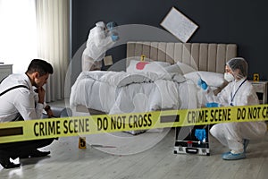 Investigators working at crime scene in messy room