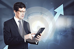 Investing and analyzing concept with happy businessman working with digital tablet on abstract raising arrows and diagram