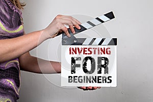 Investing for Beginners. Woman holding a movie clapper
