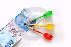 Investing with yellow, green and red darts and 100 Turkish lira on a white background, and Turkish lira for an accurate investment