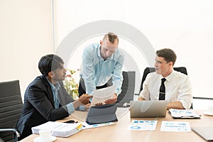 Investment advisor meeting of three businessmen analyzing company financial report,