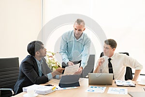 Investment advisor meeting of three businessmen analyzing company financial report,